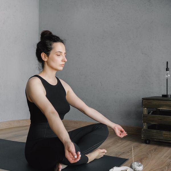 Smiling pregnant women sitting on yoga mats in a circle.